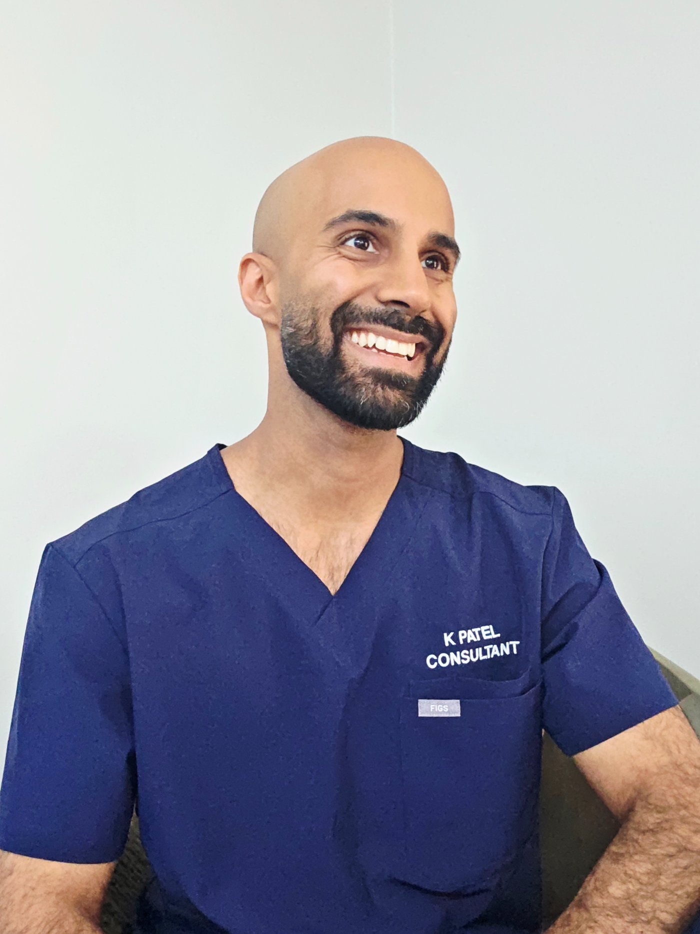 Portrait of Dr Kunal Patel in consultant scrubs, looking off-camera.